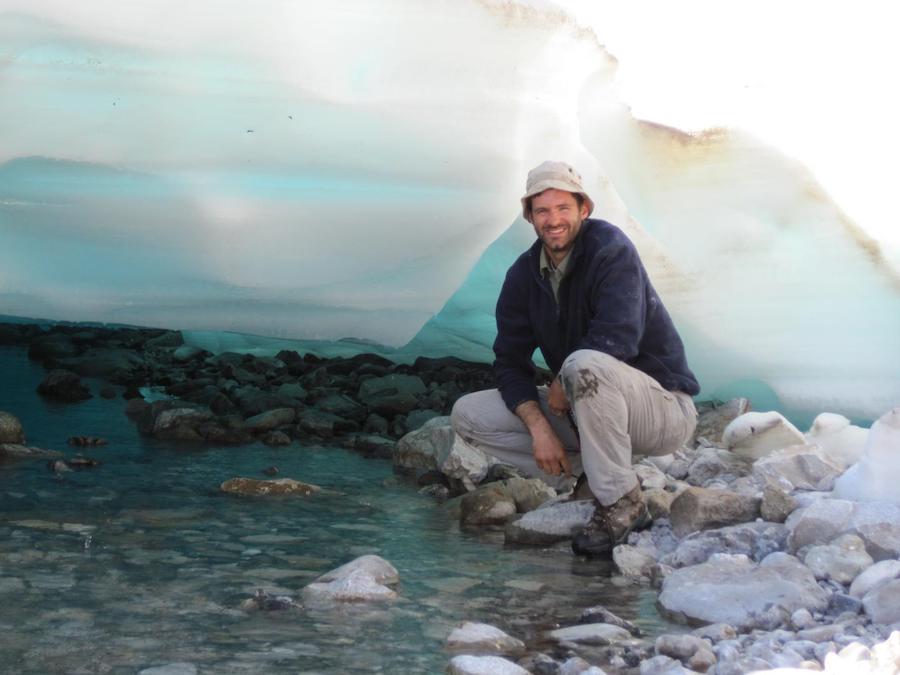 Mark C. Urban, Prof. of Ecology & Evolutionary Biology, Univ. of Connecticut, stands under a sheet of aufeis in Alaska.