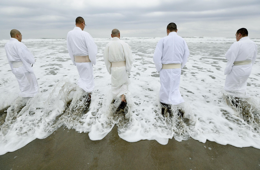 Buddhist priests entering the sea in the Tairausuisho district of Iwaki, Fukushima Prefecture, to pray for those swept away by the tsunami of March 11, 2011. (Photo: Japan Times/KYODO.)